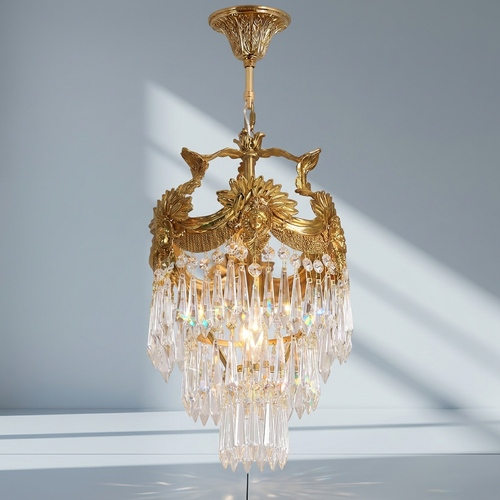 Antique brass mini crystal chandelier against a cool gray studio background with diagonal window light